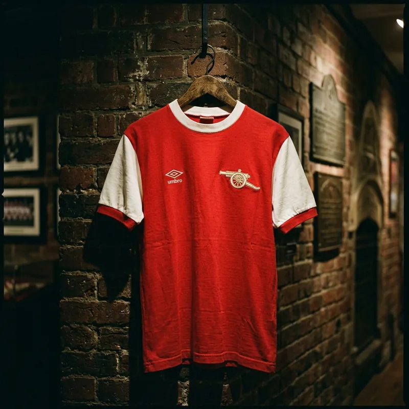 Vintage Arsenal red and white classic shirt displayed on dark brickwork