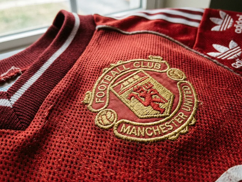 Close-up macro detail of embroidered retro football kit crest and textured mesh fabric